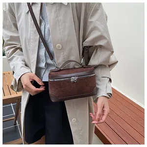 Détail du sac photo en daim marron avec garniture en cuir et fermetures éclair coeur