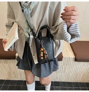 Detail of black woven texture mini crossbody bag with ethnic wooden bead tassel