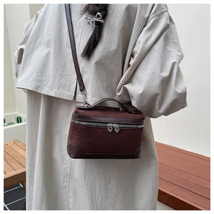 Détail du sac bandoulière en daim marron avec zips en cœur et poignées en cuir