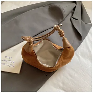 Sac hobo en daim marron givré avec bandoulière nouée sur blazer gris et literie