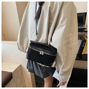 Détail d'un sac bandoulière noir en forme de boîte avec zips argentés en forme de cœur