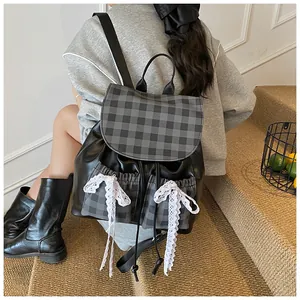 Detail of black leather backpack with grey plaid panels and white lace bow accents