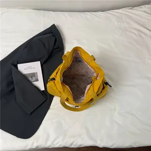Detail van de gele shopper met merkvoering en trekkoord aan de zijkanten voor aanpassing