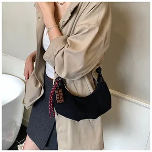 Détail du sac demi-lune en daim noir avec bandoulière nouée et breloque chocolat