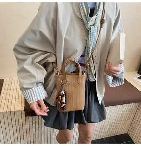 Detail of brown woven texture mini crossbody bag featuring decorative wooden bead tassel