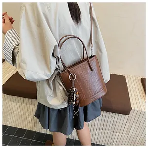 Detailed weave pattern on dark brown bucket bag featuring unique wooden bead charm