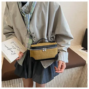 Détail d'un sac boîte en daim jaune moutarde avec zips en cœur et poignée noire
