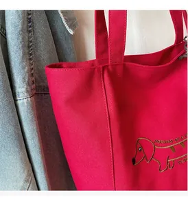 Close-up of red canvas tote bag showing high-quality stitching and dog embroidery detail