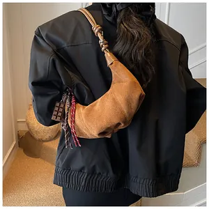 Gros plan d'un sac demi-lune en cuir dépoli marron avec bandoulière nouée sur l'épaule