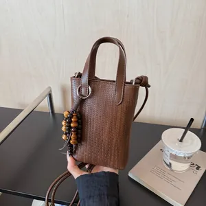 Brown woven texture mini crossbody bag with retro wooden bead charm and shoulder strap