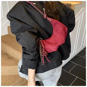 Détail du sac demi-lune en daim rouge avec bandoulière nouée bordeaux et charme en cordon
