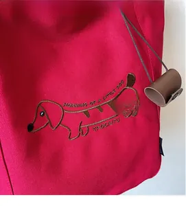 Detailed view of red canvas bag featuring exquisite brown dachshund embroidery and texture