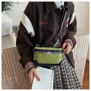Vue détaillée d'un sac bandoulière en daim vert avec fermetures éclair en cœur
