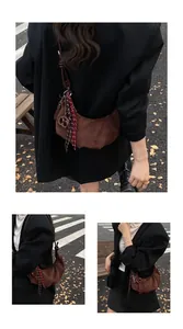 Détail du sac hobo en daim marron foncé avec pendentifs et bandoulière large élégante