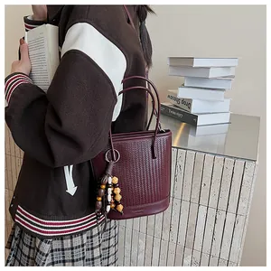 Detail of red bucket bag featuring woven texture and wooden bead tassel decoration