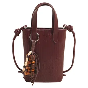 Vertical square burgundy woven leather crossbody bag with wooden bead pendant charm
