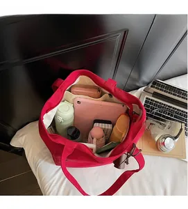 Top view of red canvas tote bag showing interior compartments with laptop and daily items