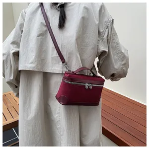 Détail du mini sac en daim bordeaux avec fermeture éclair cœur argentée et coins en cuir