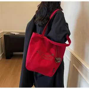Detail of red canvas tote bag with dachshund embroidery and mini hanging leather pouch