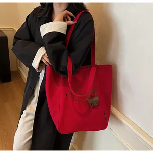 Detail of red canvas tote bag with dachshund print and mini leather charm accessory