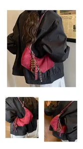 Détail du sac croissant en daim rouge avec pendentif chocolat et pompon tissé