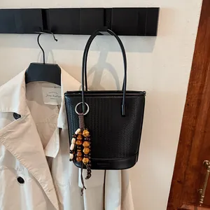 Chic black woven bucket bag with leather texture and vintage wooden bead tassel ornament