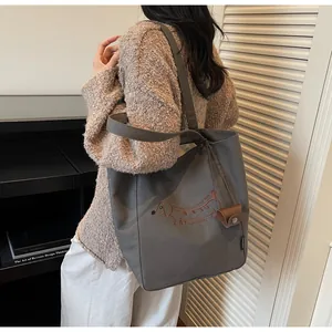Detail of grey canvas tote bag featuring embroidered dachshund and small brown pouch charm