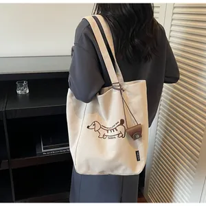 Detailed close-up of embroidered dachshund and morning text on white canvas tote bag
