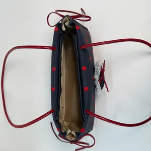 Borsa a tracolla in tela a pois blu scuro con fiocco rosso e bordo in pizzo bianco