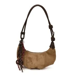 Sac hobo demi-lune marron en cuir dépoli avec pompon tressé coloré sur fond blanc