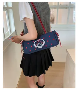 Dettaglio borsa in tela blu scuro a pois rossi con toppa a cuore in pizzo sul lato