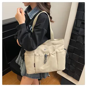 Detail van gebroken witte Oxford tote bag met meerdere zakken en trekkoord gespen