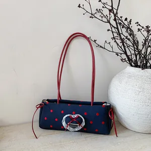 Borsa a spalla in tela a pois con fiocco rosso e dettaglio cuore in pizzo su marmo