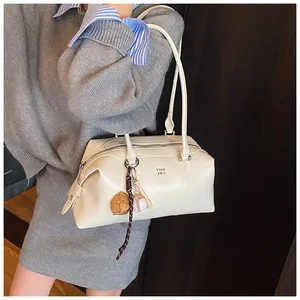 Nahaufnahme einer weißen glänzenden Bowlingtasche aus Leder mit Baseball-Anhänger und Logo