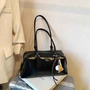 Glänzende schwarze Schultertasche aus Wachsleder mit modischen Anhängern und Logo
