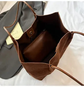 Detailed view of brown suede tote bag with magnetic closure and interior zipper pouch