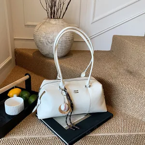 Minimalistische weiße Schultertasche aus gewachstem Leder mit Logo auf schwarzem Buch