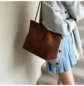 Detail view of large dark brown suede tote bag with fine texture on woman shoulder