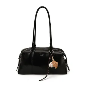 Minimalistische schwarze glänzende Achseltasche aus Leder mit Baseball-Anhänger