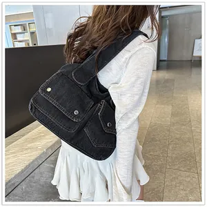 Detail der schwarzen Denim-Tasche mit Silberschnallen und Kontrastnähten an der Schulter