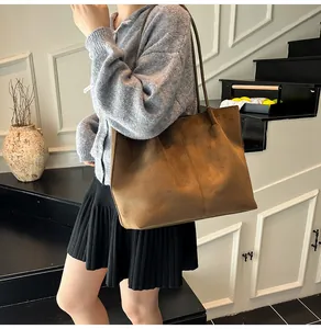 Detailed view of the brown matte suede tote bag shown on a model in a minimalist setting