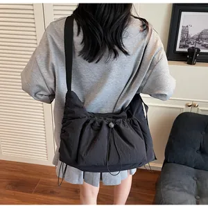 Detailansicht der schwarzen Nylon-Umhängetasche mit Falten, Kordelzug und Schultergurt