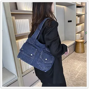 Detail der dunkelblauen Denim-Schultertasche mit Metallschnappen und Vordertaschen