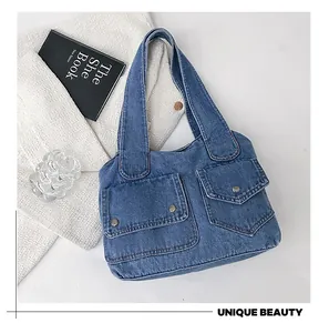 Detailansicht der Denim-Tasche mit großen Fronttaschen und metallischen Druckknöpfen