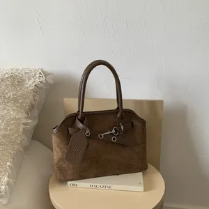 Classic coffee brown suede tote bag with silver hardware on a minimalist wooden table