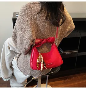 Detail of red dumpling bag featuring suede leather texture and oversized bow handle