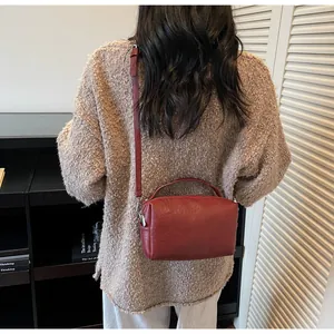Gros plan d'un sac seau vintage rouge foncé en similicuir avec bandoulière réglable