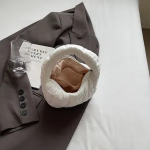Fashionable white quilted puffer handbag on a brown blazer with a modern aesthetic