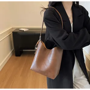Détail du sac seau en cuir marron foncé avec charm en perles de bois et logo gaufré