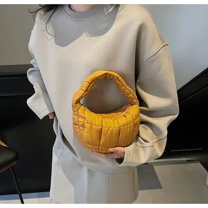 Detailed view of yellow quilted puffer handbag featuring a crescent shape and stylish texture